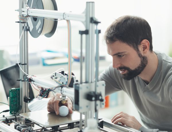 Young designer engineer using a 3D printer in the laboratory and studying a product prototype, technology and innovation concept