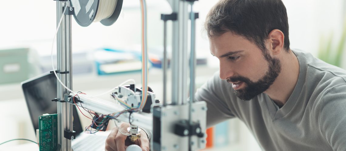 Young designer engineer using a 3D printer in the laboratory and studying a product prototype, technology and innovation concept